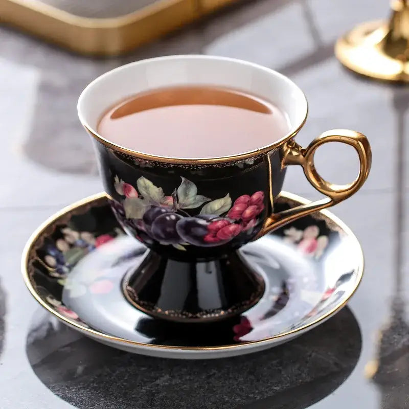 Elegant black porcelain tea cup with gold trim and floral grape design on matching saucer in decorbites bone teaware set