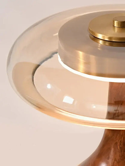 A modern walnut table lamp with a clear glass dome brass accents and wooden base for bedroom use french style