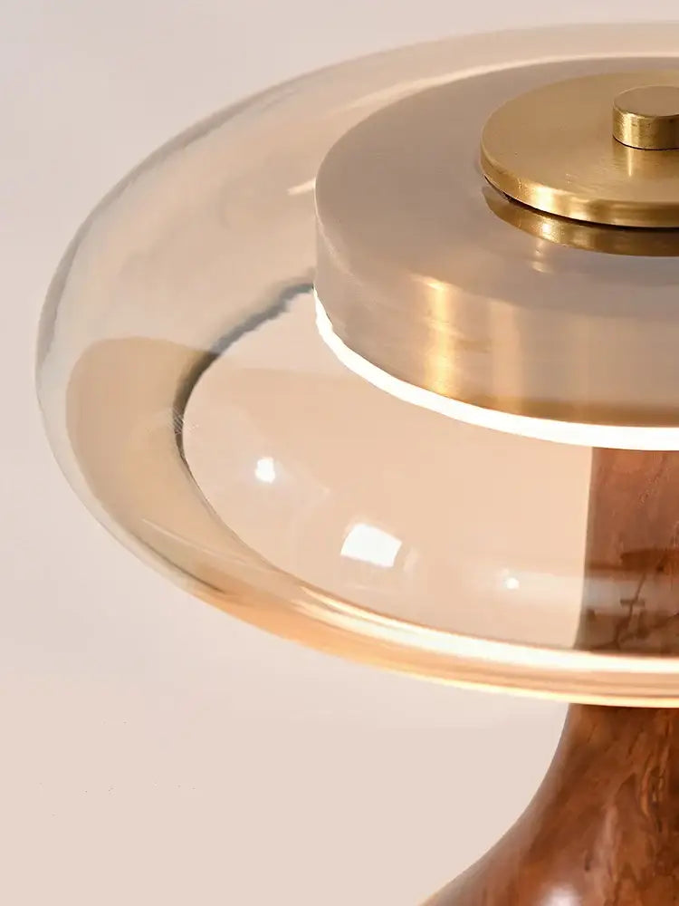 A modern walnut table lamp with a clear glass dome brass accents and wooden base for bedroom use french style
