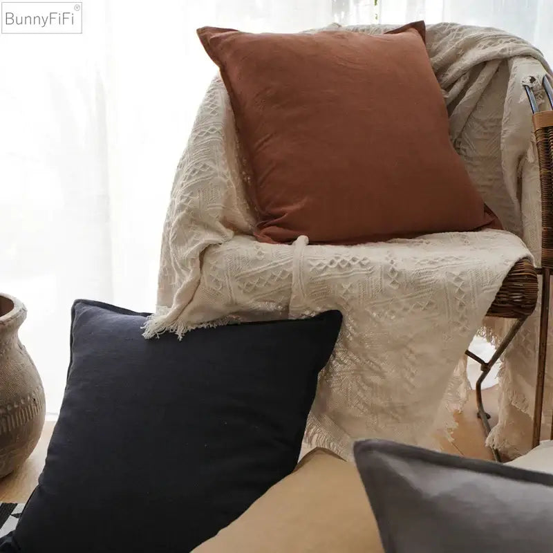 A rust-colored soft decorbites linen pillow cover with plush texture on a woven chair with off-white lace throw decorbites linen pillow