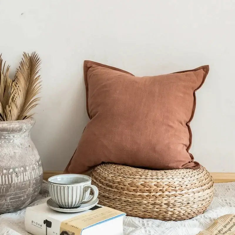 A soft rust-colored decorbites linen pillow cover with textured surface and neatly stitched edges for living room decor