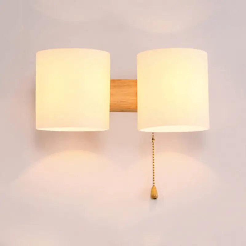 Warm-toned frosted fabric wall lamp with natural wood center and brass pull chain for bedroom wall lighting direct wired electric
