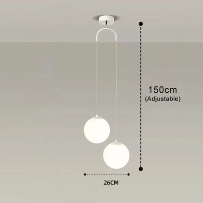 Frosted glass pendant light with white spherical shades and adjustable brass and black hanging length for dining room