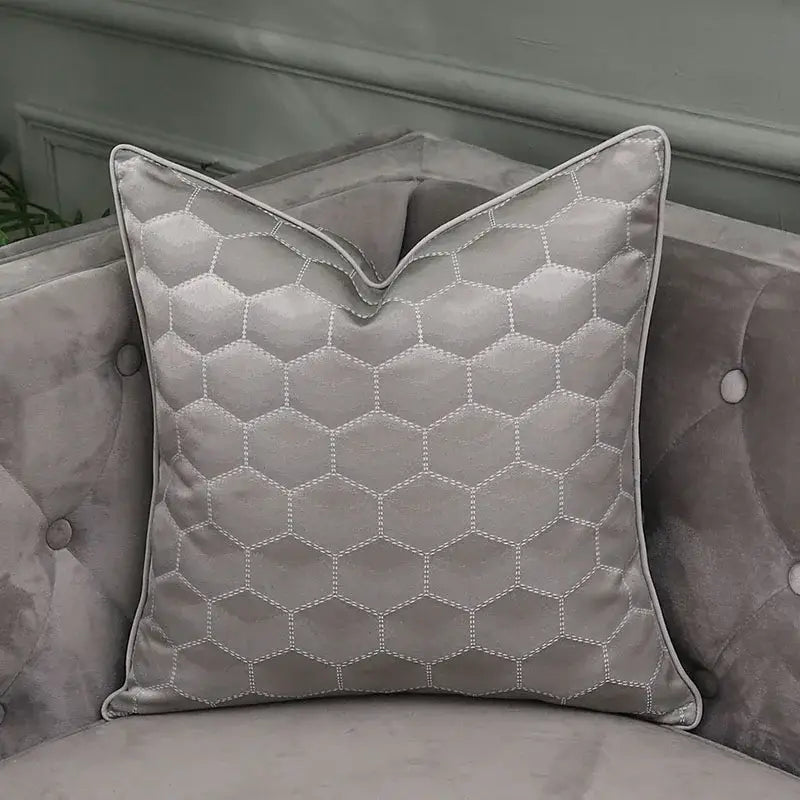 A sleek gray cushion with hexagonal quilting and piping on a velvet sofa for decorbites frosted gold satin pillow covers