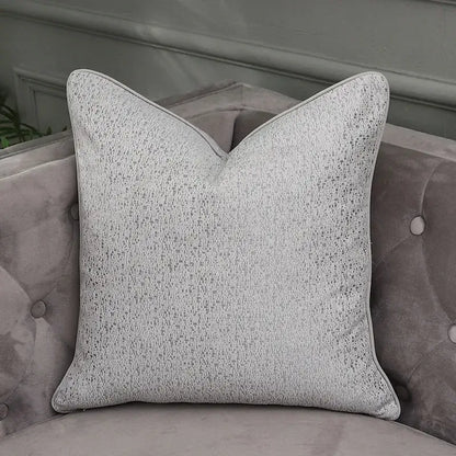 A square light gray textured throw pillow with subtle speckled pattern and piping for decorbites frosted gold pillow covers