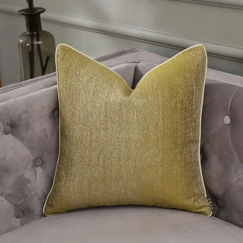 A frosted gold satin velvet pillow cover with white trim on a tufted gray sofa for decorbites frosted gold decor