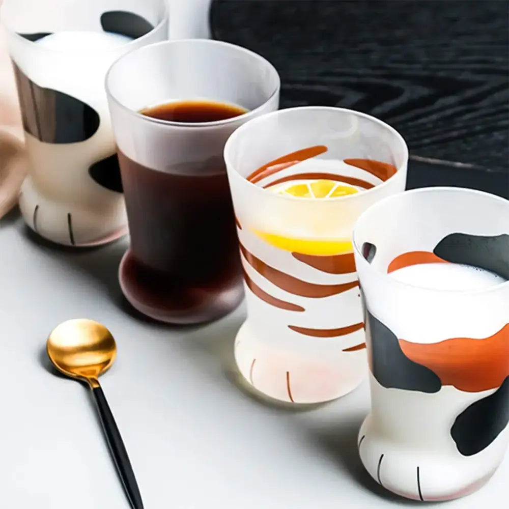 Set of four frosted glass shot glass mugs with orange and black cat paw decorbites cat paw designs on white base