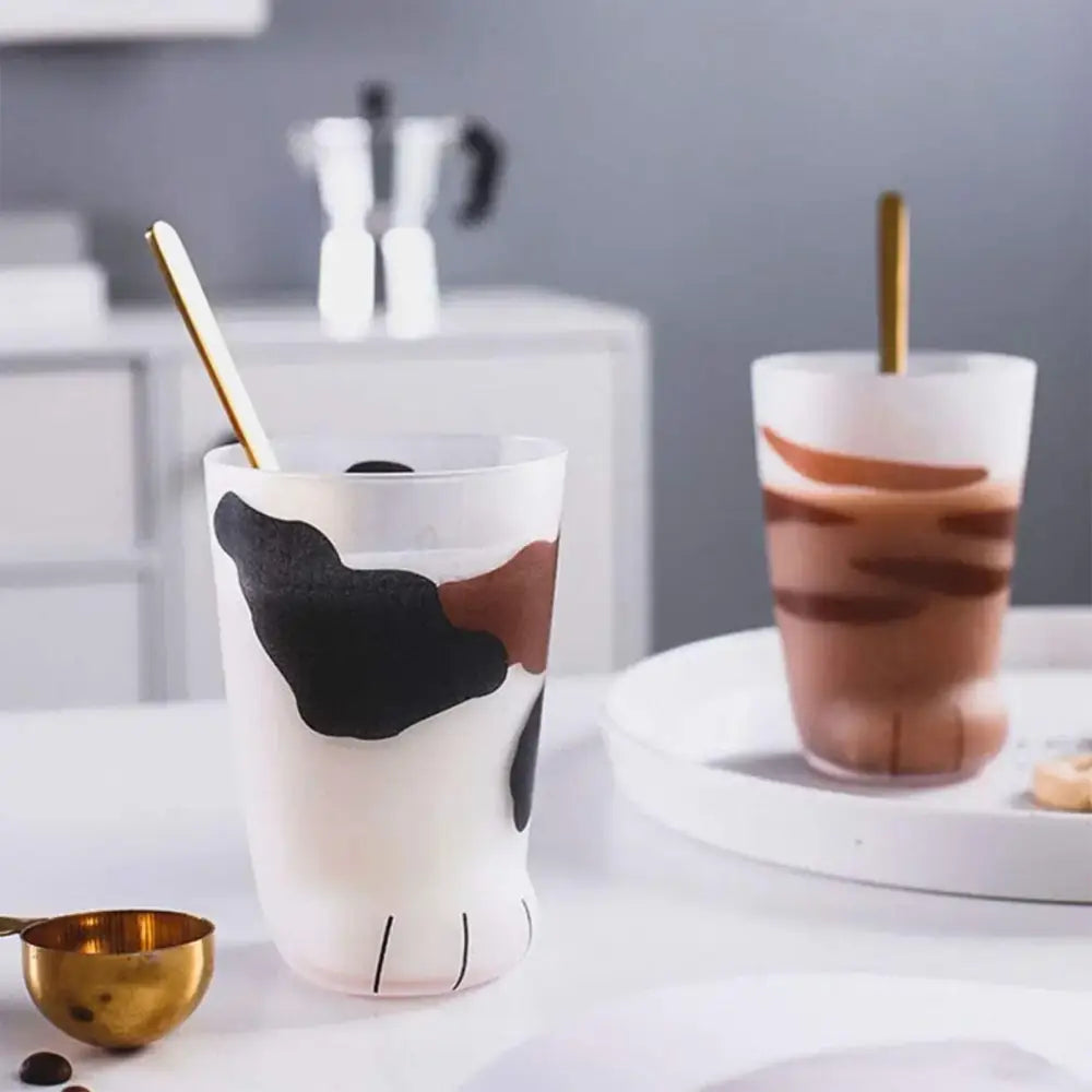 White frosted glass shot glass with black and brown cow print and decorbites cat paw foot details for cat paw shot set