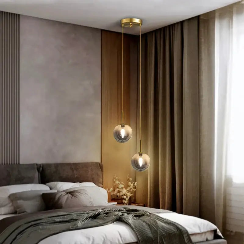 Two spherical frosted white and smoke gray globe pendant lights with gold-toned metal fixtures for dining room