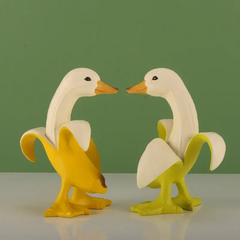 Funny white banana duck sculpture featuring two white duck figurines with orange beaks inside yellow banana peels for living room decor