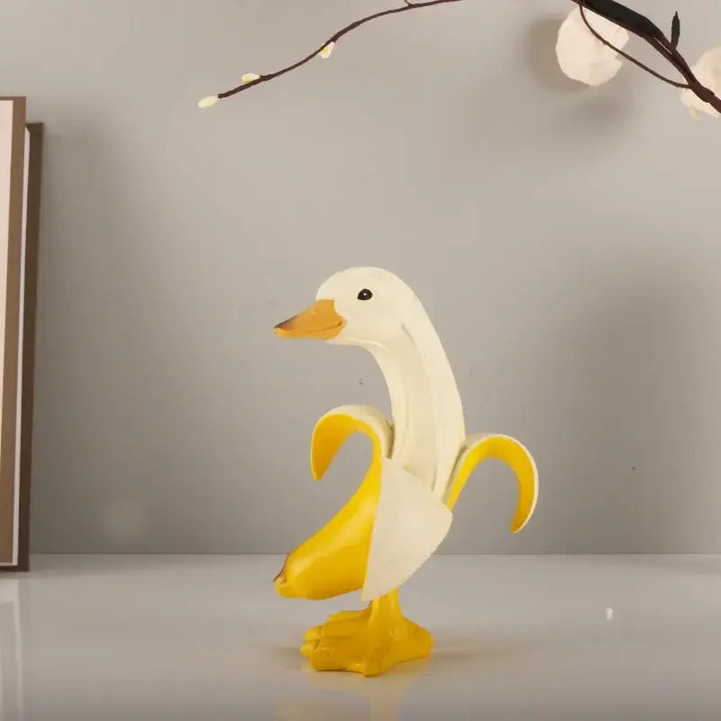 White duck sculpture with yellow beak and feet designed as a whimsical banana duck sculpture for living room decor
