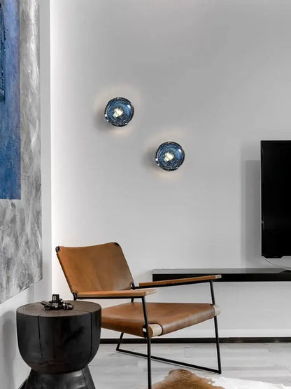 Two circular blue glass wall sconce lamps with textured reflective surfaces for living room lighting