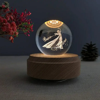 A glowing transparent crystal ball music box featuring an engraved elsa figure on a warm wooden rotating base