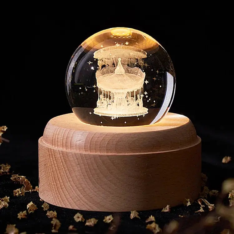 A glowing transparent crystal ball music box with an engraved carousel illuminated by warm light for bedroom decor