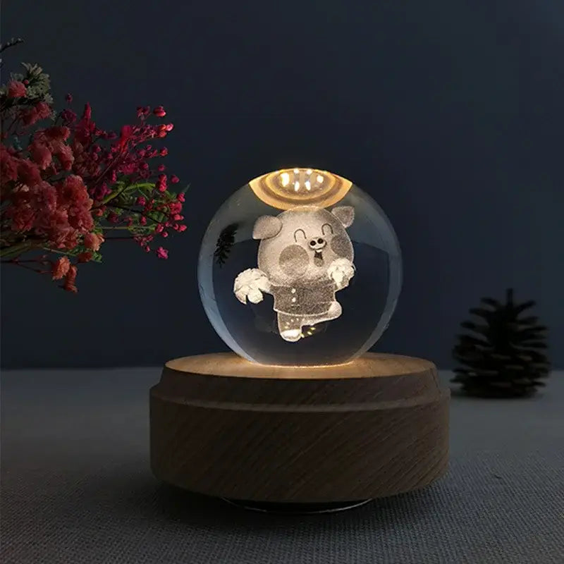 A glowing transparent crystal ball music box with a cartoon pig inside on a rotating wooden base for bedroom decor