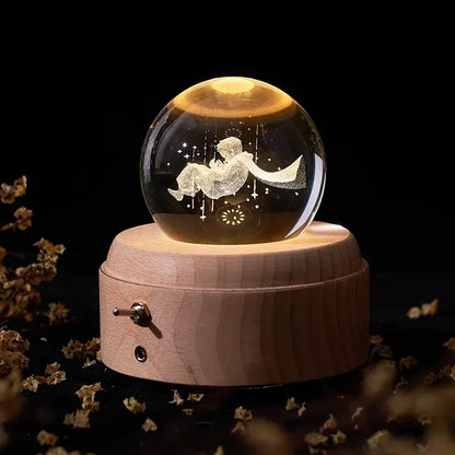A glowing crystal ball music box with an engraved boy on a crescent moon illuminated by warm light