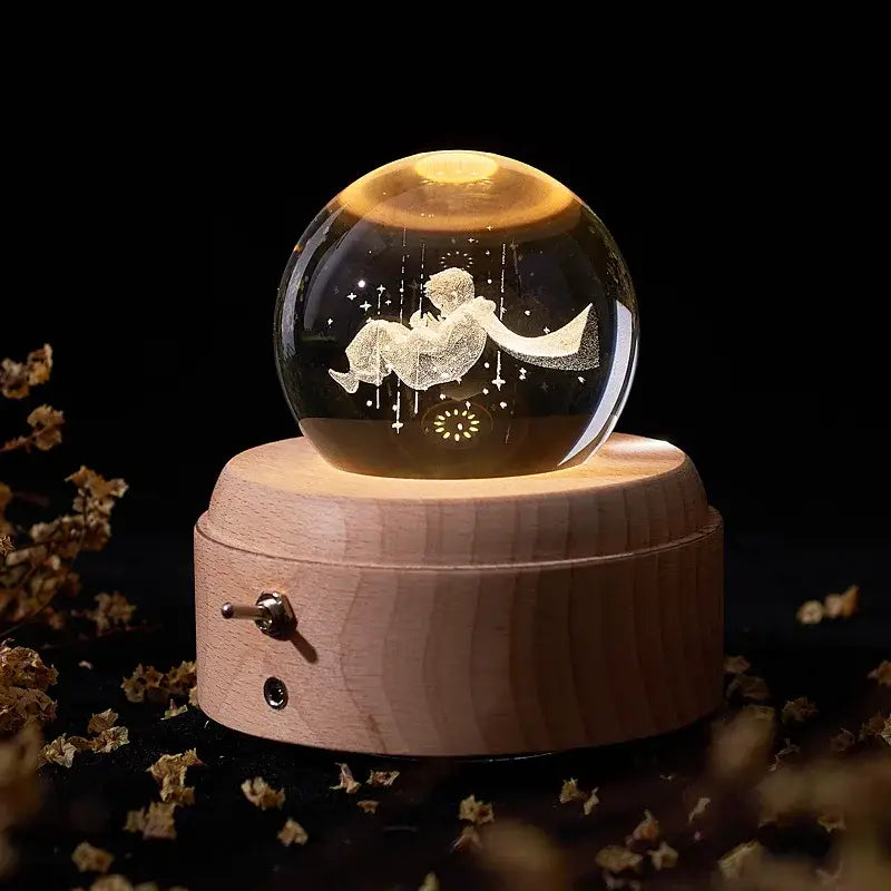 A glowing crystal ball music box with an engraved boy on a crescent moon illuminated by warm light