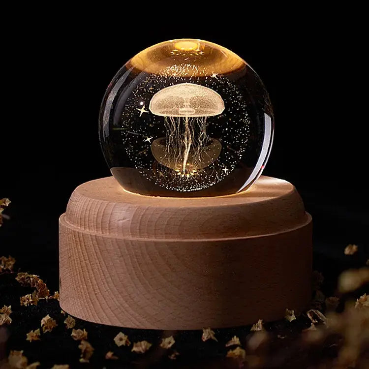A glowing translucent jellyfish crystal ball music box resting on a light wooden base for bedroom light glow
