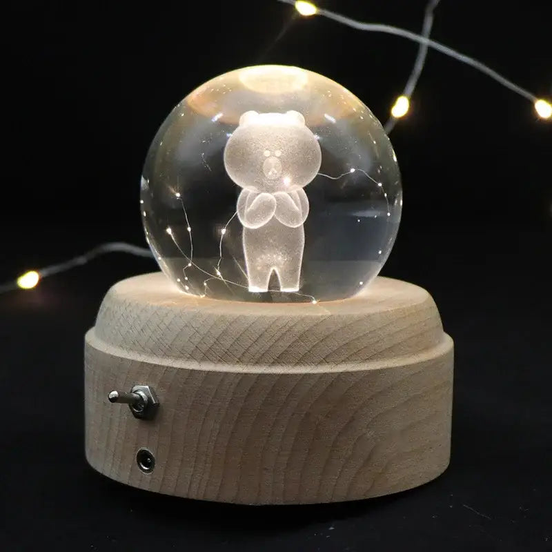 A translucent glass crystal ball music box with an engraved white bear inside on a light wooden rotating base