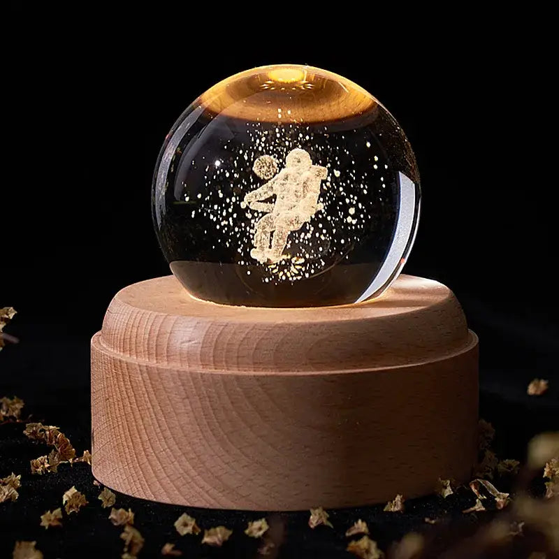 A golden astronaut figurine encased in a crystal ball music box with a wooden base and light glow for bedroom decor