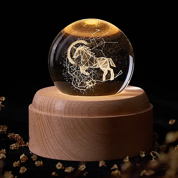 A glowing aries constellation crystal ball music box with geometric etching on a light wooden base for bedroom decor