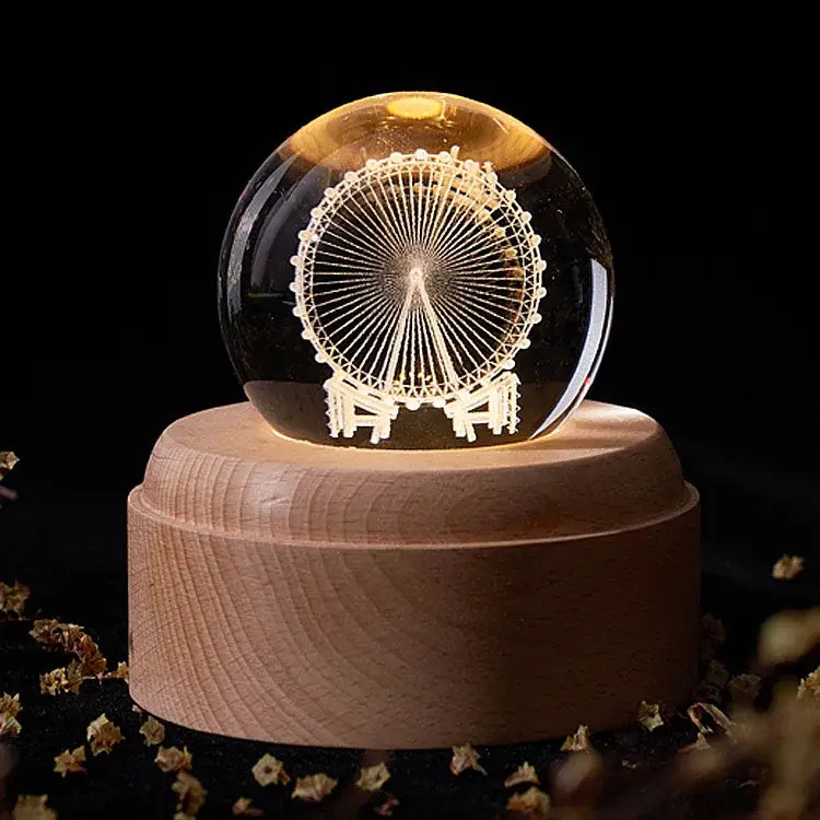 A glowing transparent crystal ball music box with an etched white ferris wheel on a wooden base for bedroom decor