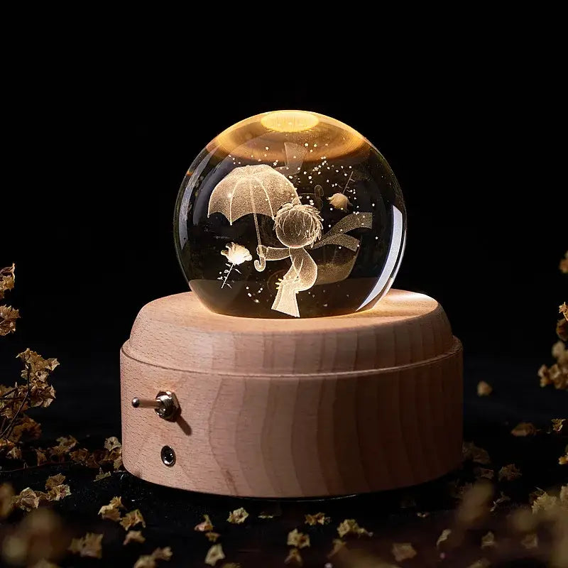A warm-lit crystal ball music box with an engraved child illustration on a light wooden base for bedroom glow