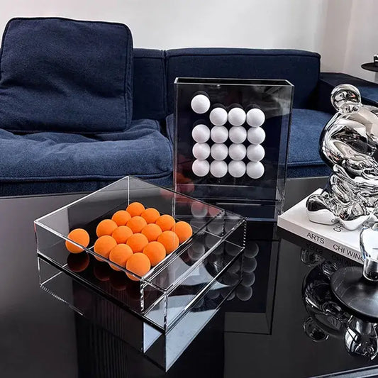 Clear acrylic geometric abstract acrylic ball ornament storage box with mirrored base holding orange spheres for display