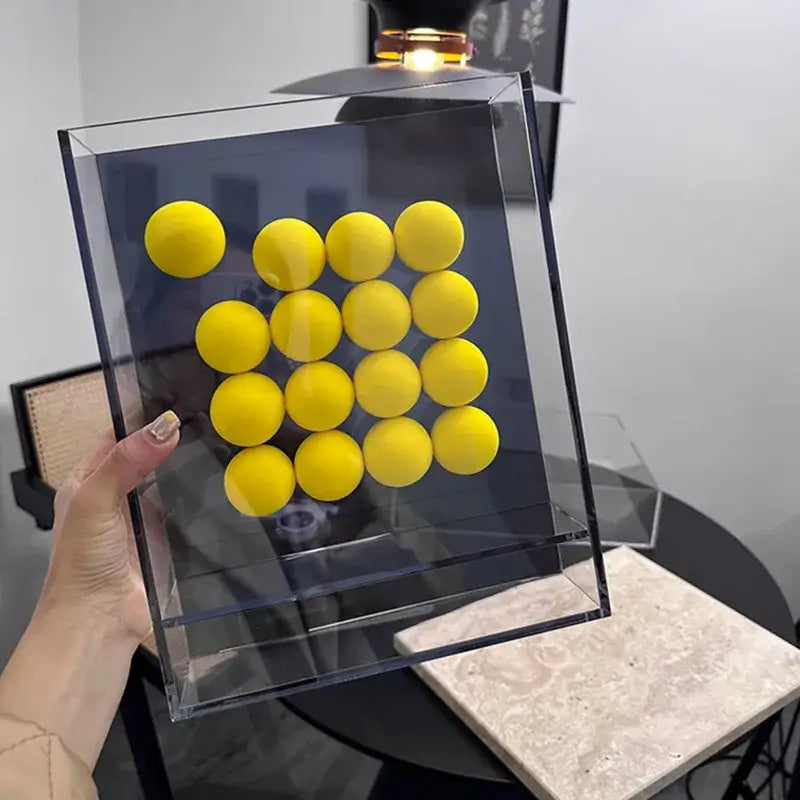 Clear acrylic display box featuring a grid of bright yellow abstract acrylic ball ornaments for geometric living room decor