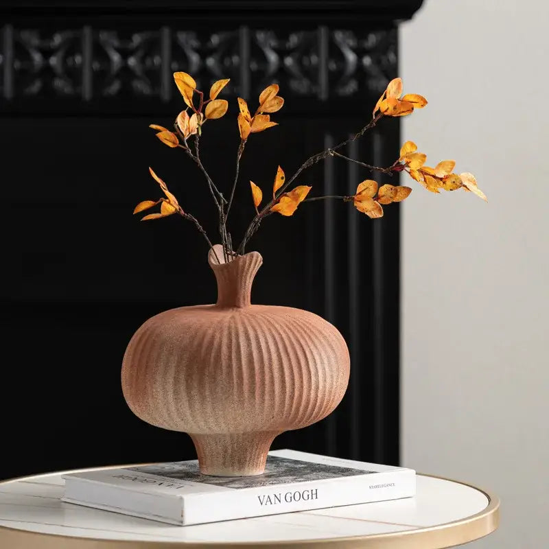 Terracotta geometric abstract ceramic vase with vertical ribbed texture and flared neck holding dried orange leaves decorbites geometric abstract decor