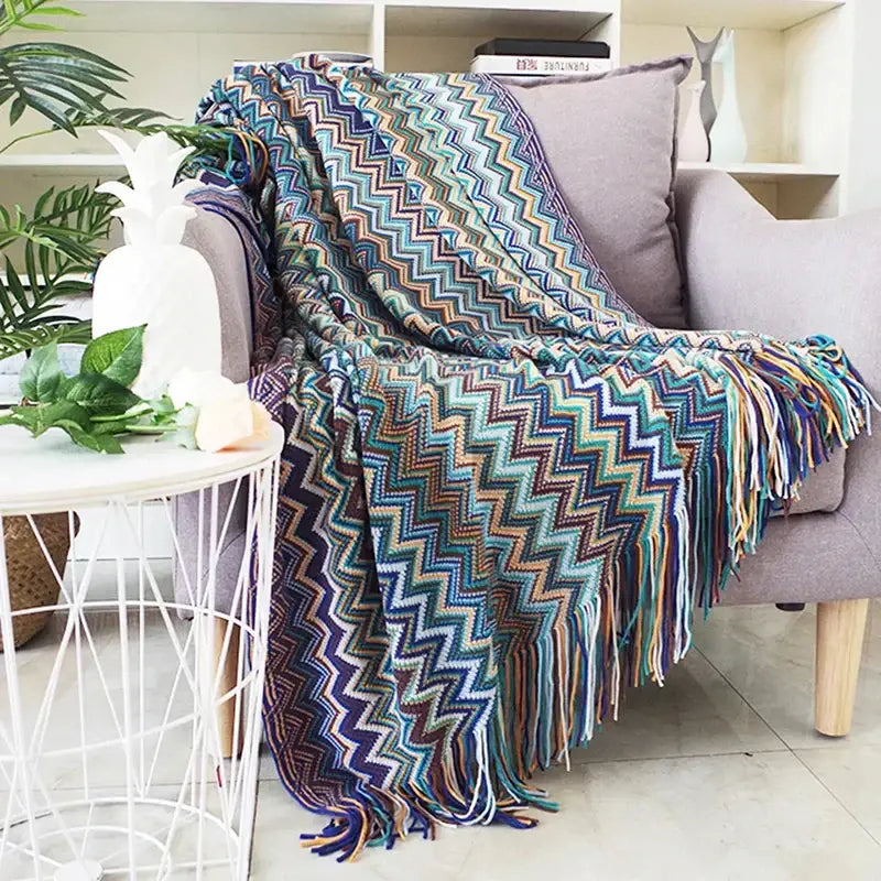 A vibrant geometric aztec baja knit throw blanket in mustard and blue with fringe detailing for living room decorbites