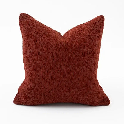 A rust-colored square throw pillow with plush textured fabric from a geometric black and cream pillow cover set for living room
