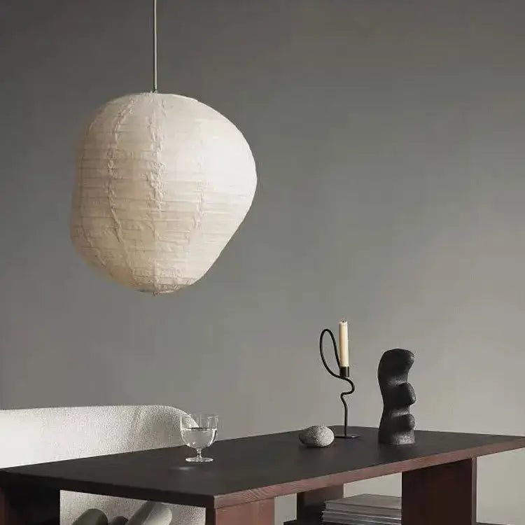 Off-white textured paper lantern hanging from slender rod in geometric black metal candlestick candelabrum decorbites centerpiece