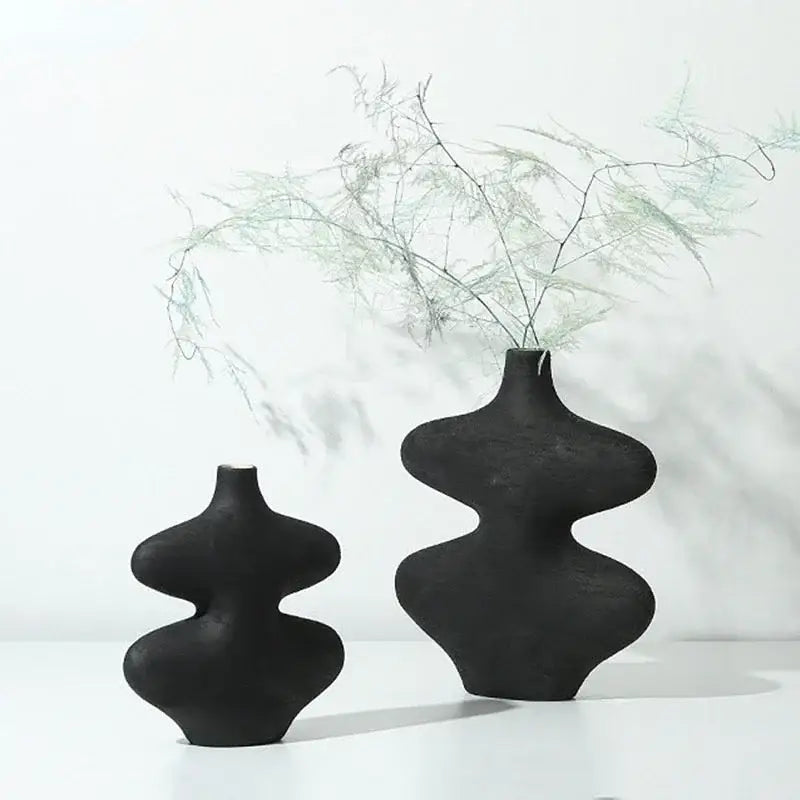 Two sleek matte black geometric ceramic vases with sculptural forms in a modern ceramic vase set for living room decorbites