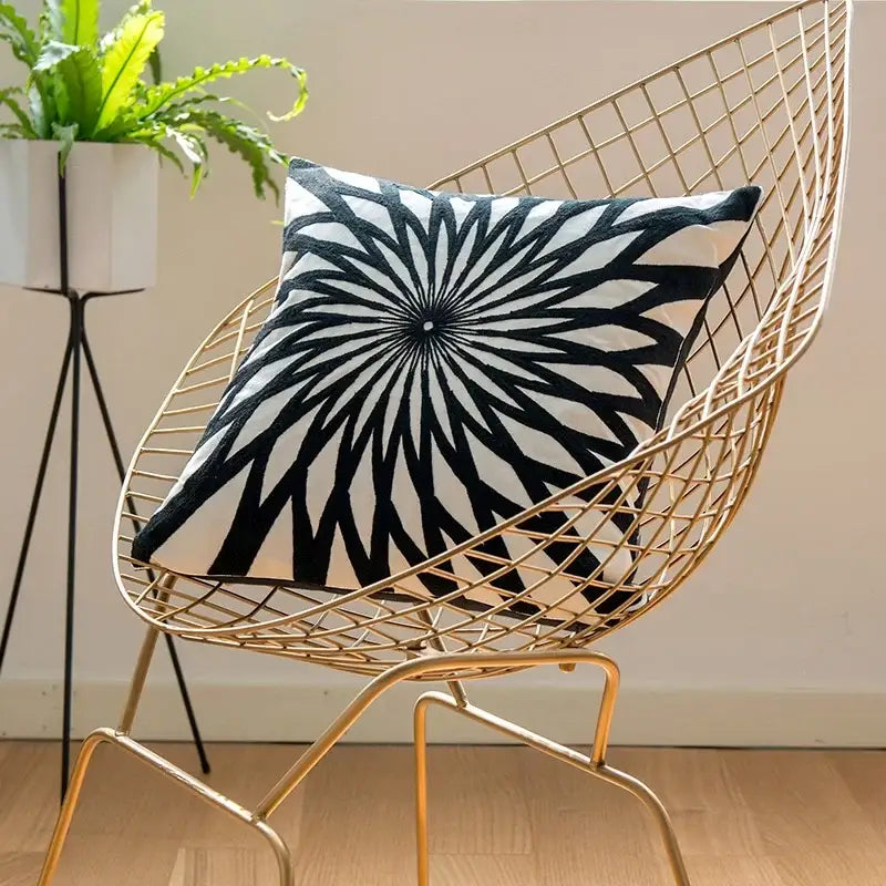 Geometric black white embroidered cushion cover with radial sunburst pattern on gold wireframe chair decorbites black white
