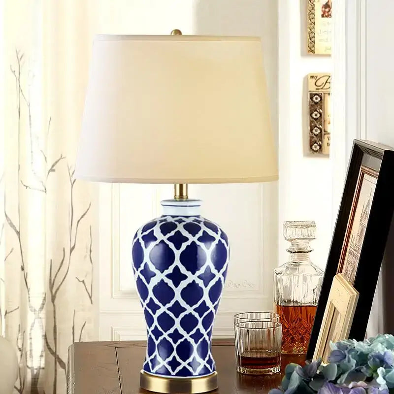 Blue and white patterned ceramic table lamp with cream fabric shade and gold base for bedside table use
