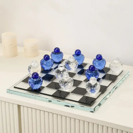 A geometric blue and clear glass chess set with faceted pieces on a black and white checkered glass board