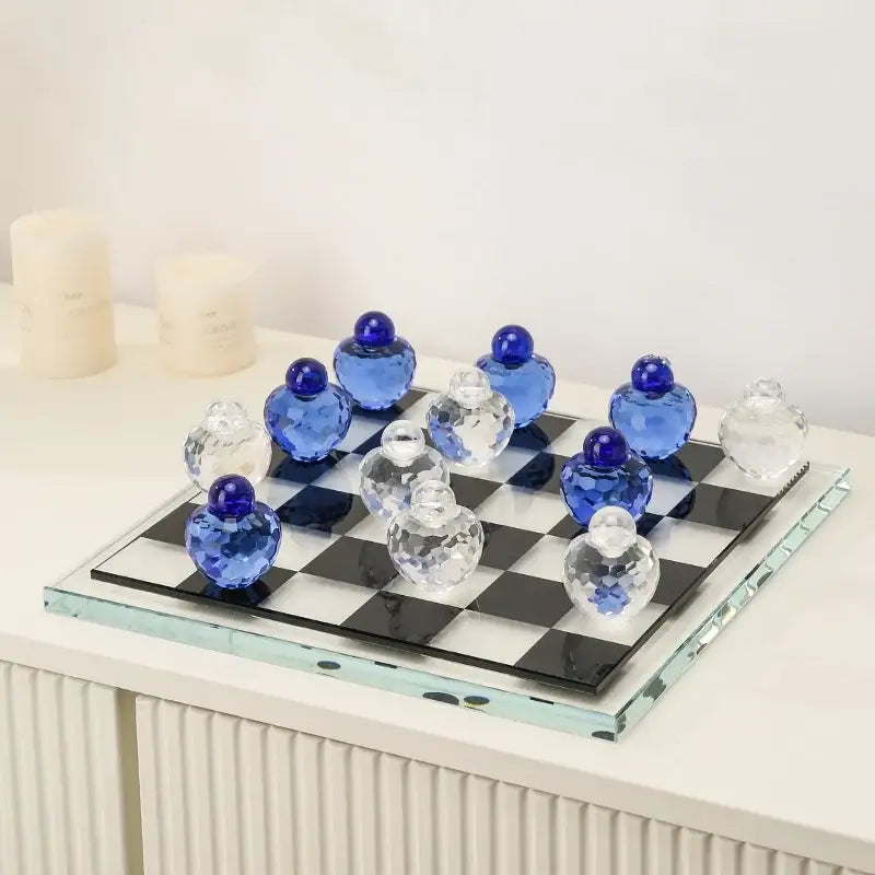 A geometric blue and clear glass chess set with faceted pieces on a black and white checkered glass board