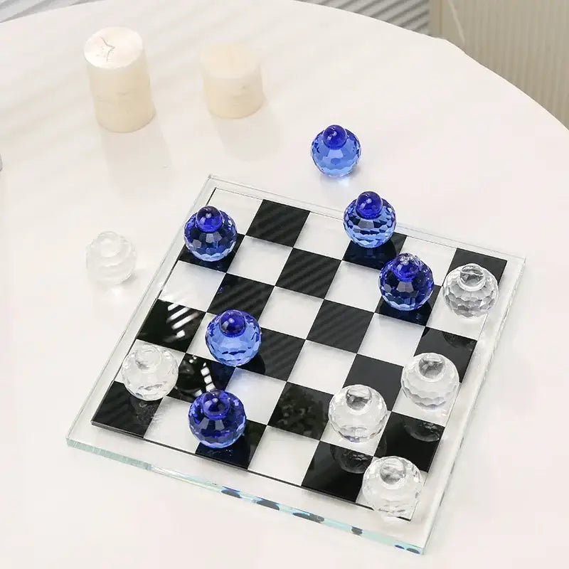 A sleek glass chess set with blue and clear faceted crystal pieces on a black and white checkered board for living room decor