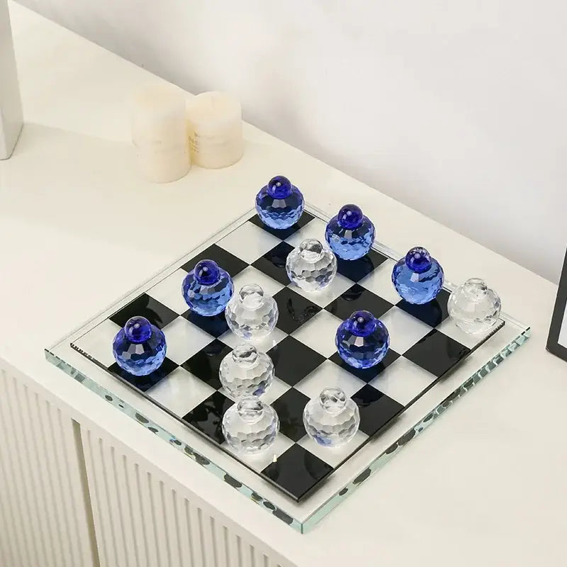 A sleek geometric blue and clear glass chess set with translucent crystal pieces on a black and white board for decor