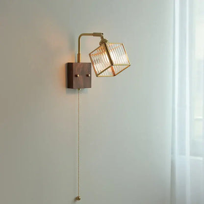 Brass led wall light with geometric blue glass cube shade, adjustable arm, dark wood base, and pull-chain switch by decorbites