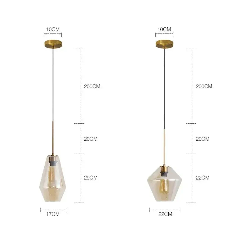 Two modern geometric pendant lights with brass-finished metal and clear glass shades for kitchen lighting
