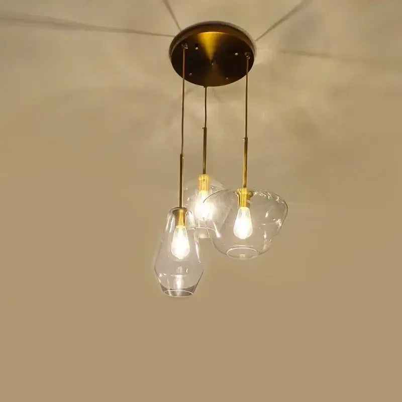 Brass-finished pendant light with three clear glass shades ideal for kitchen glass chandelier lighting