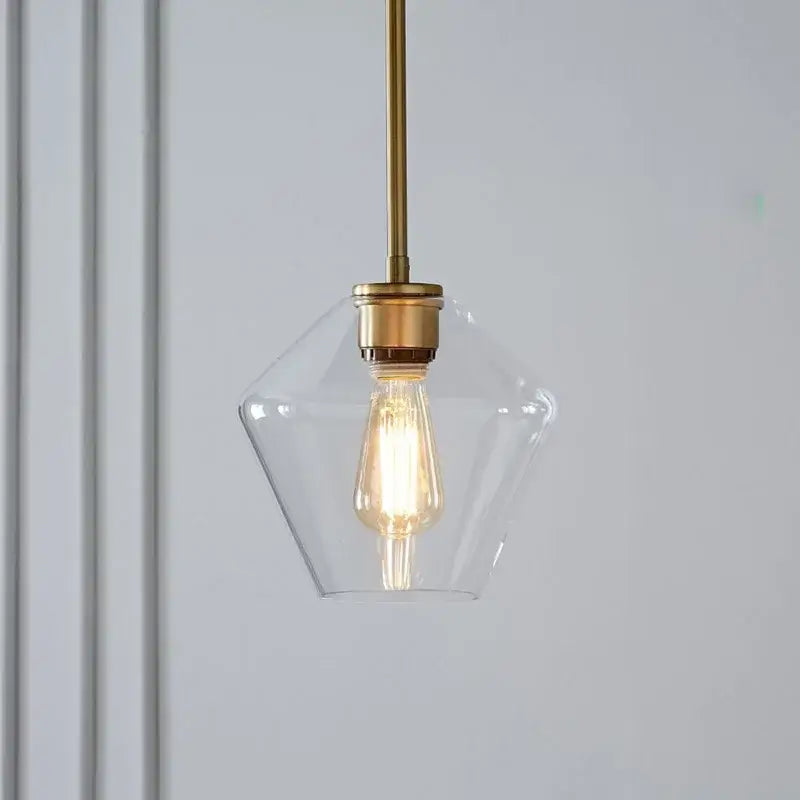 A glass pendant light with brass finish metal rod and exposed filament bulb in geometric pendant lights set for living room