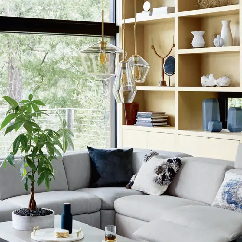 Modern geometric glass pendant lights set with brass accents hanging above a gray sectional sofa for living room