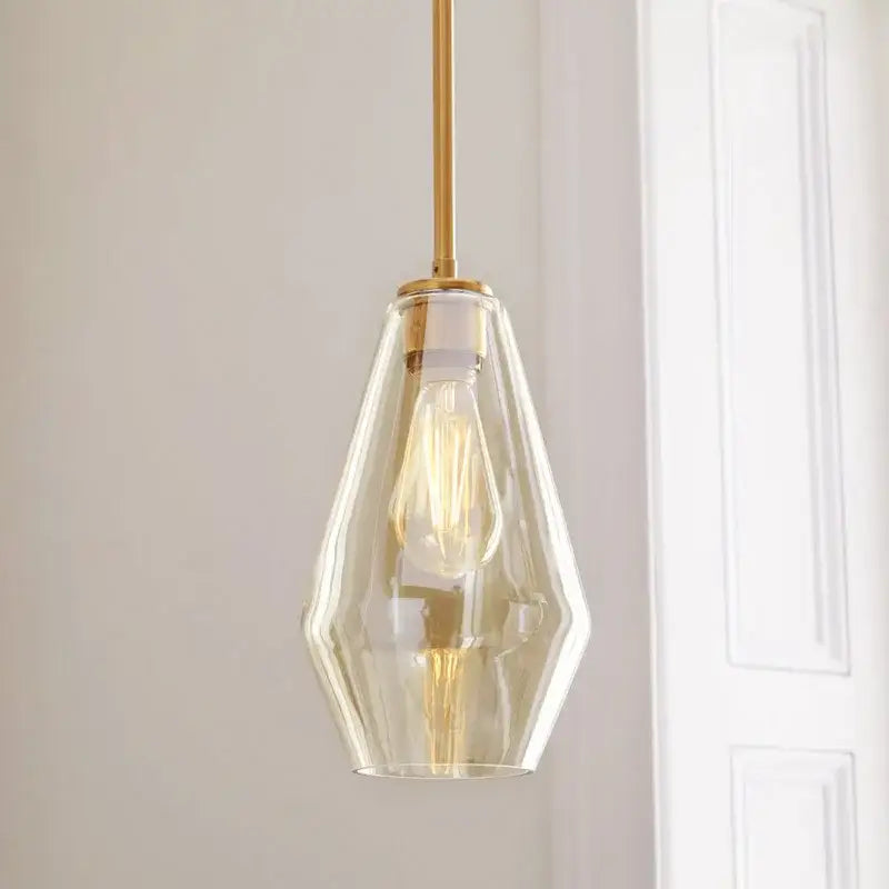 A sleek geometric brass glass pendant lights set featuring faceted glass pendant light and exposed filament bulb for living room