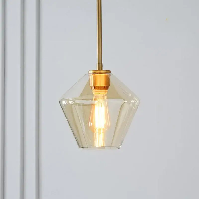 A warm-toned geometric glass pendant light with brass-finished rod in a pendant lights set for living room