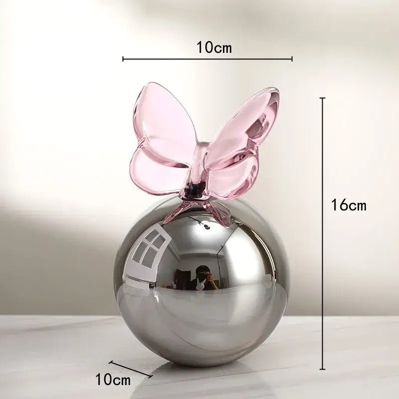 A geometric butterfly crystal ball with a sleek silver sphere and translucent pink glass butterfly for home decor
