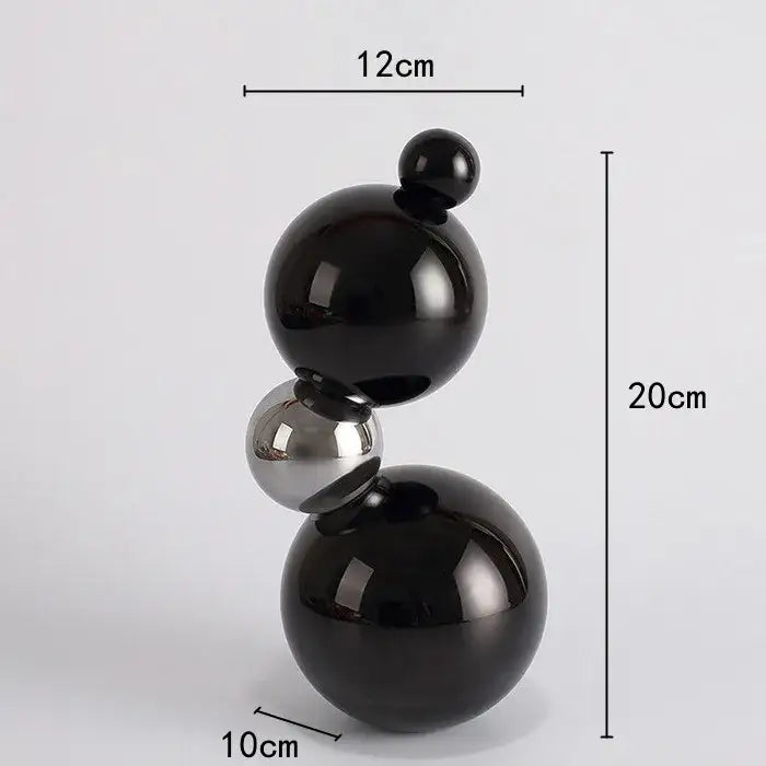 A sleek geometric butterfly crystal ball home decor featuring three stacked glossy black and silver spheres