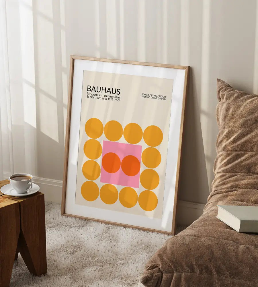 A framed DecorBites™ bauhaus geometric canvas print with yellow and pink circles in a light wood frame for home decor